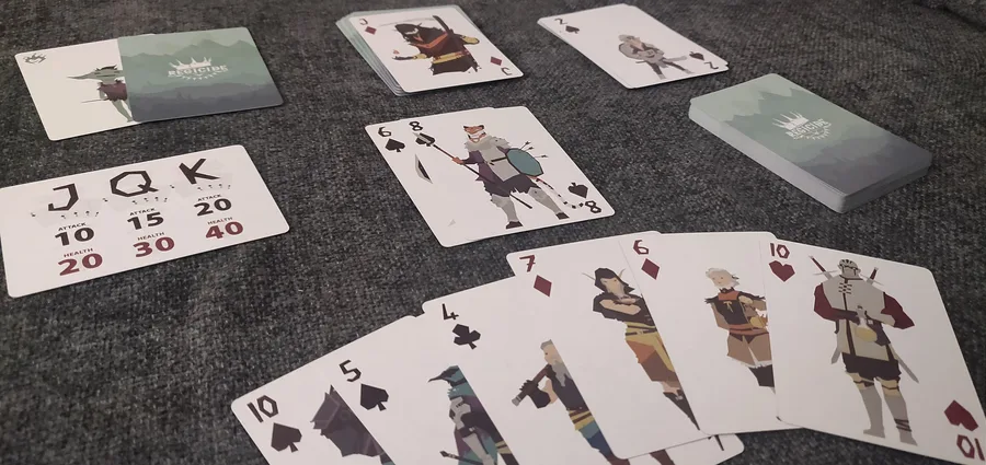 Partida en solitario de Regicide con cartas en la mano, el mazo de la taberna, la carta de referencia de enemigos y el mazo del castillo.